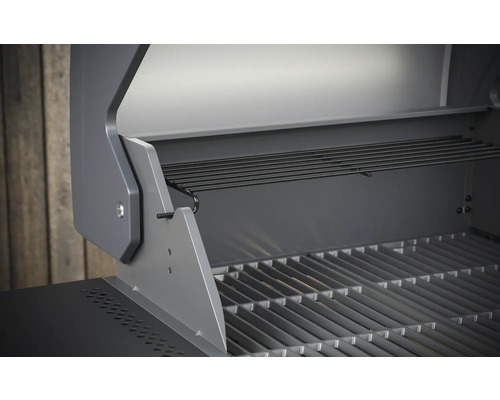 Vnitřní pohled na plynový gril s grilovacím roštem a ohřívacím roštem.