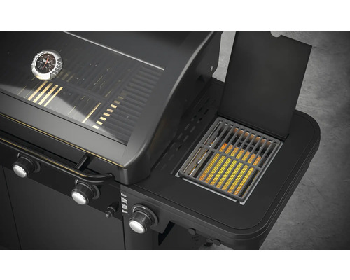 Detailní pohled na černý plynový gril s bočním hořákem a ukazatelem teploty.