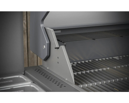 Detailní pohled na otevřený plynový gril s grilovacím roštem a ohřívacím roštem