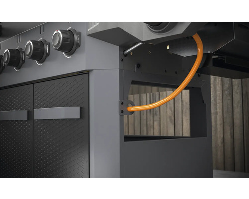 Detailní pohled na plynový gril s ovládacími knoflíky, dvířky a plynovou hadicí