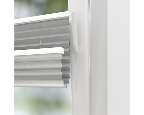 Detailní pohled na bílou skládanou žaluzii na okně