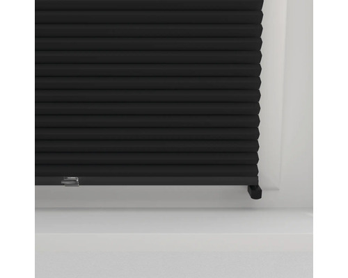 Detail černého plisovaného závěsu před oknem