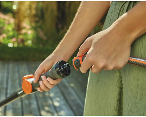 Osoba připojuje zahradní hadici ke konektoru.