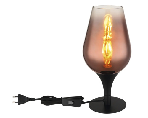 Dekorativní stolní lampa ve tvaru poháru se zapnutou žárovkou