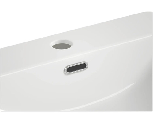 Detailní pohled na bílé umyvadlo s přepadem a otvorem pro baterii