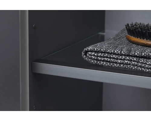 Detail koupelnové skříňky se skleněnou policí, ručníkem a kartáčem