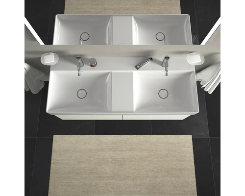 Pohled shora na dvojité umyvadlo s bateriemi, miskami na mýdlo, ručníky a koberec v koupelně.