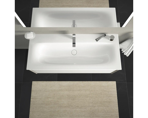 Pohled shora na koupelnu s umyvadlem, zrcadlem, baterií, dávkovačem mýdla, zubní pastou, ručníkem a koupelnovou předložkou