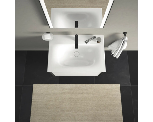 Pohled shora na koupelnu s umyvadlem, zrcadlem, ručníkem a koupelnovou předložkou