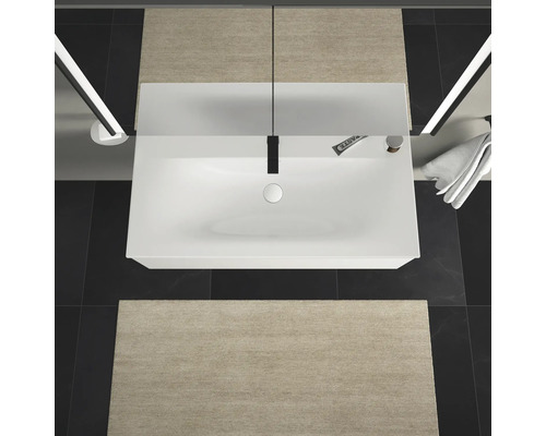 Pohled shora na koupelnu s umyvadlem, baterií, ručníkem a koupelnovými předložkami