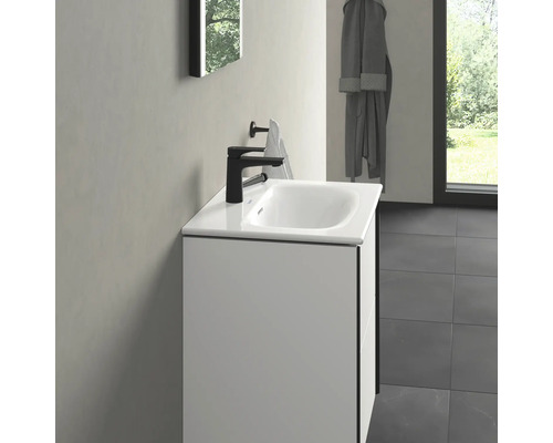 Umyvadlo s černou baterií a držákem na ručníky v koupelně