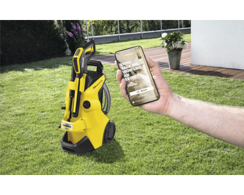 Žlutý vysokotlaký čistič Kärcher K4 Power Control s chytrým telefonem na trávníku