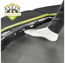 Detailní pohled na trampolínu se systémem ochrany nohou a nohou v bílé ponožce na skákací plachtě.