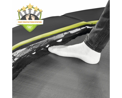 Detailní pohled na trampolínu se systémem ochrany nohou a nohou v bílé ponožce na skákací plachtě.