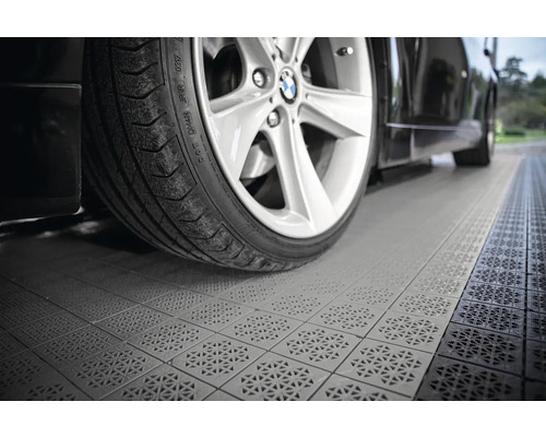 Auto stojí na garážových dlaždicích s drenážním vzorem.