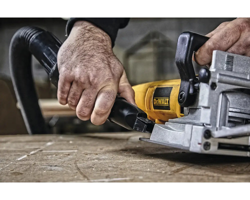 Ruka drží hadici vysavače na kotoučové pile Dewalt.