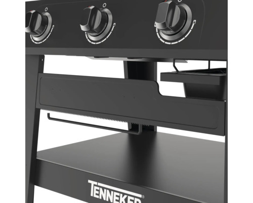 Detailní pohled na černý plynový gril s otočnými knoflíky, držákem na papírové ručníky a úložnou plochou značky Tenneker.