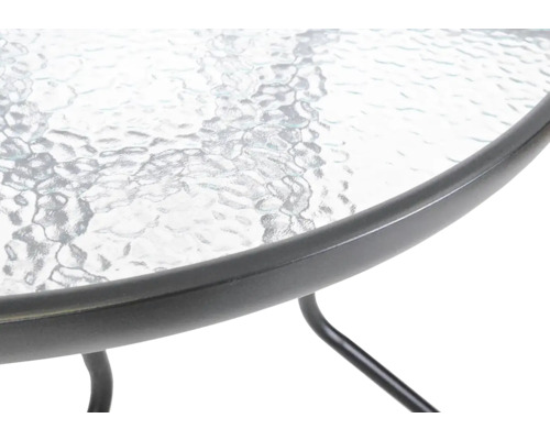 Detail zahradního stolu se skleněnou deskou a kovovým rámem