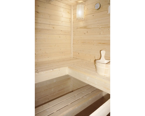 Interiér sauny s dřevěnými lavicemi, lampou, teploměrem a dřevěným vědrem