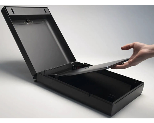 Otevřený, černý nástěnný trezor s rukou vkládající dovnitř ploché elektronické zařízení