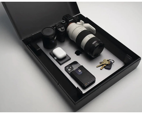 Elektronická zařízení, jako je fotoaparát, notebook a sluchátka v černé úložné krabici.