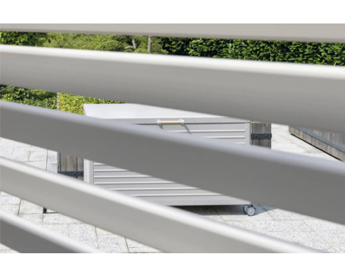 Zahradní scéna s kovovým úložným boxem na kolečkách, pohled skrz plot