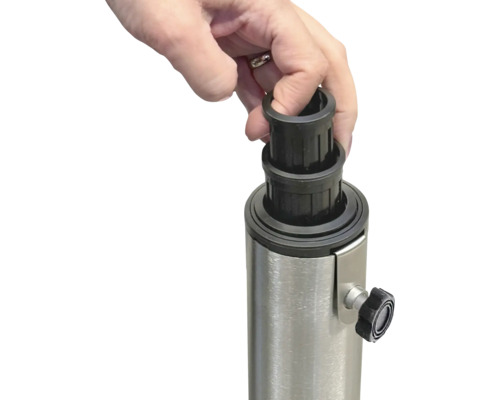 Ruka nasazuje černou redukční objímku na kovový stojan pro slunečník.