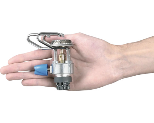 Ruka drží přenosný kempingový vařič