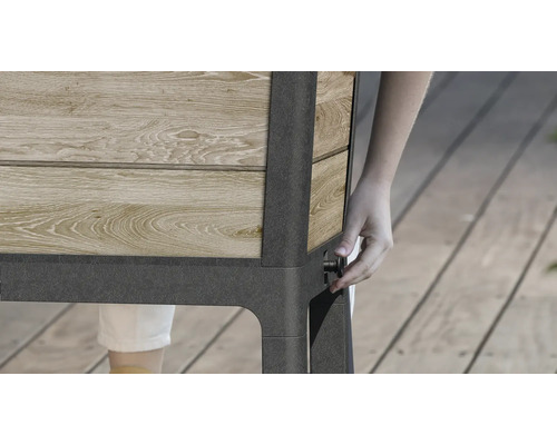 Detailní pohled na vyvýšený záhon ze dřeva a kovu s osobou ovládající knoflík