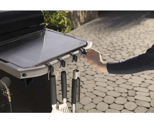 Detailní záběr grilovacího stolu s grilovacím náčiním na hácích.