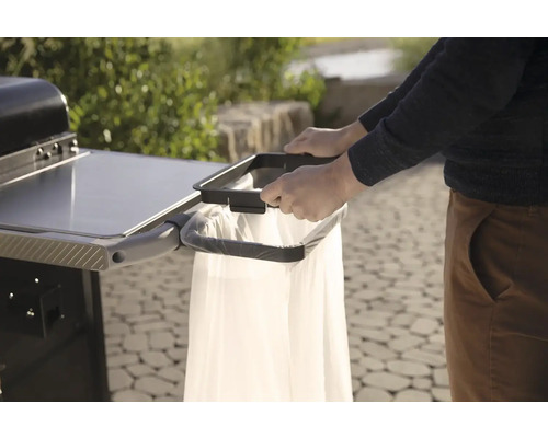 Osoba připevňuje pytel na odpadky k vozíku na gril pro čisté a praktické grilování.