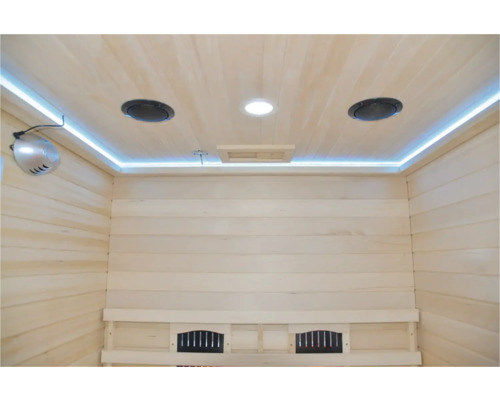 Vnitřní pohled na saunu s dřevěným obložením, osvětlením a reproduktory.