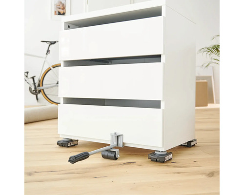 Zvedák nábytku s bílou komodou na dřevěné podlaze