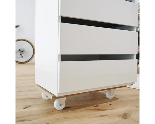 Bílý zásuvkový prvek s kolečky na dřevěné podlaze