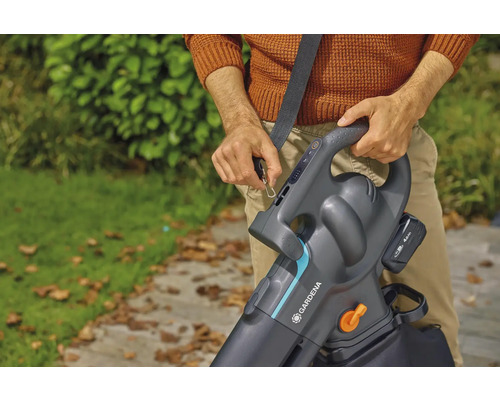 Osoba připevňuje akumulátorový vysavač listí Gardena s ramenním popruhem