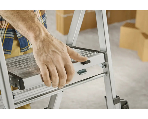 Osoba ovládá skládací schůdek z hliníku.