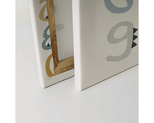 Detailní záběr na dva obrazy na plátně s písmeny a dřevěným rámem