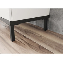 Detailní záběr bílé koupelnové skříňky s černými kovovými nohami na dřevěné podlaze