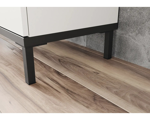Detailní záběr bílé koupelnové skříňky s černými kovovými nohami na dřevěné podlaze