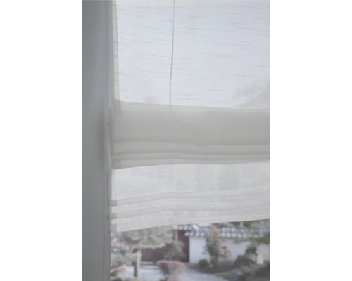 Detail bílé skládané žaluzie v okně pro soukromí a dekoraci.