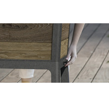 Detailní pohled na vyvýšený záhon s dřevěným obkladem a osobou ovládající otočný knoflík na straně