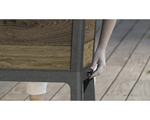 Detailní pohled na vyvýšený záhon s dřevěným obkladem a osobou ovládající otočný knoflík na straně