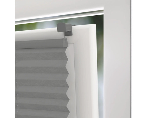 Šedá plisovaná roleta na okně s držákem pro regulaci světla