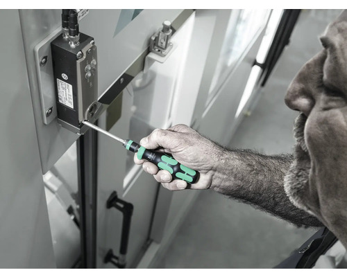 Muž používá šroubovák k utažení šroubu na elektronické součástce.