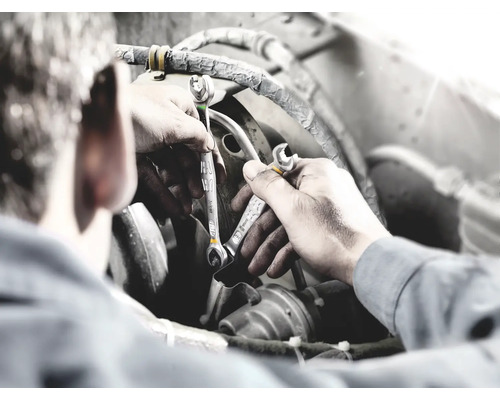 Muž pracuje se dvěma klíči na motoru.