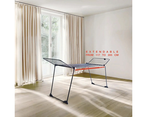 Rozkládací sušák na prádlo v interiéru před oknem se závěsy