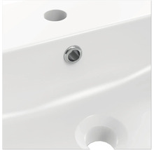 Detail bílého umyvadla s otvorem pro kohoutek a přepadem