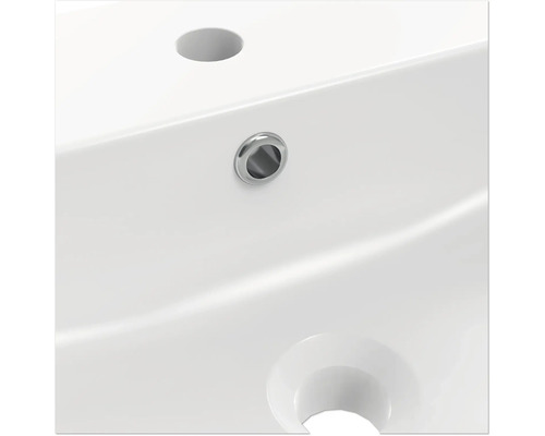 Detail bílého umyvadla s otvorem pro kohoutek a přepadem