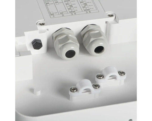 Detail bílé připojovací krabice s kabelovými průchodkami a kabelovými svorkami