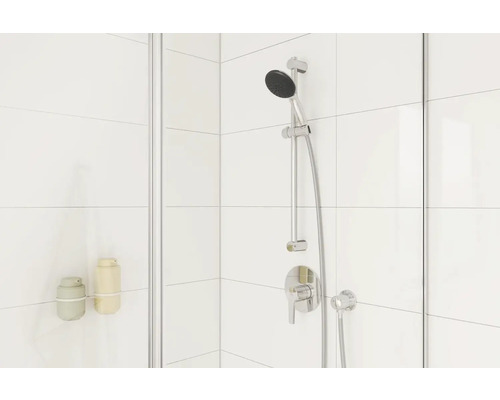 Sprcha s sprchovou baterií, sprchovou hlavicí a držákem na šampon na pozadí bílých dlaždic